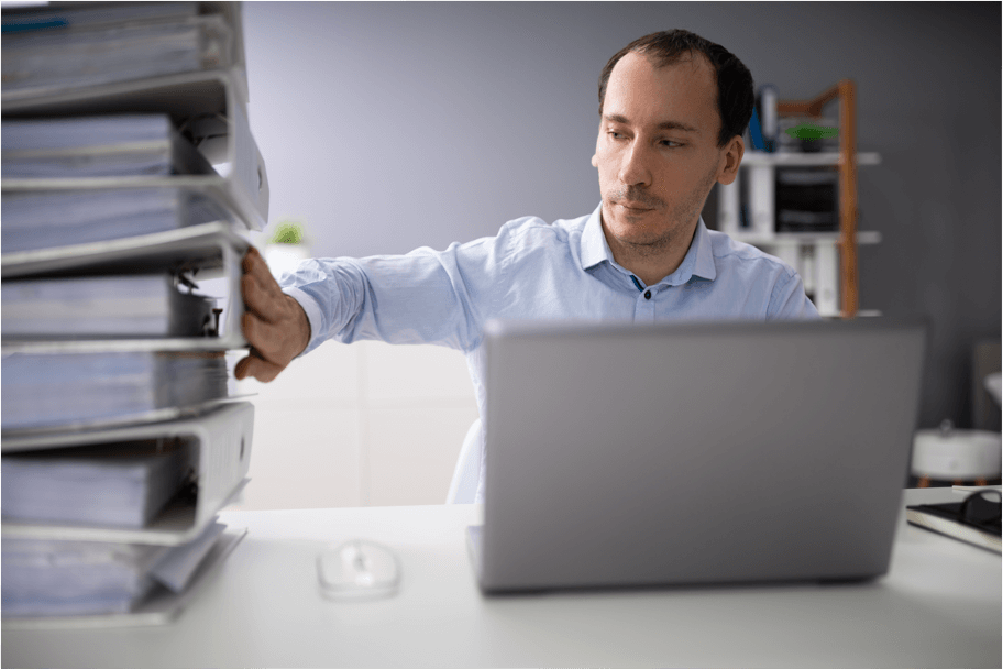 Employee working on laptop next to binders