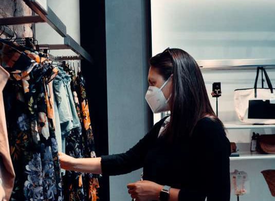 femme portant un masque et regardant des vêtements