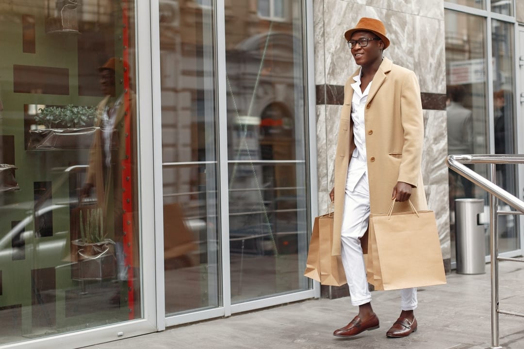 young fashionable man with shopping bag walking into a store