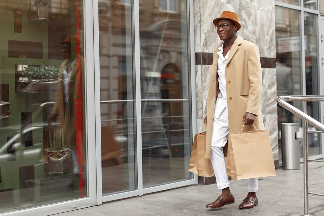 young fashionable man with shopping bag walking into a store