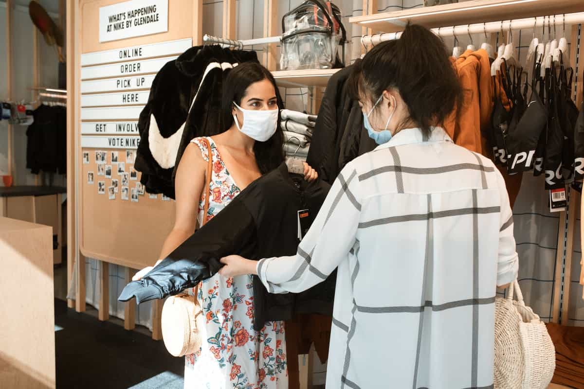 Two women shopping clothes together and wearing masks